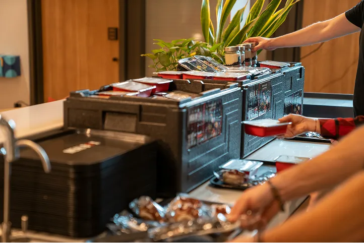 Sıcak yemeklerini kutulardan alan kişiler görseli